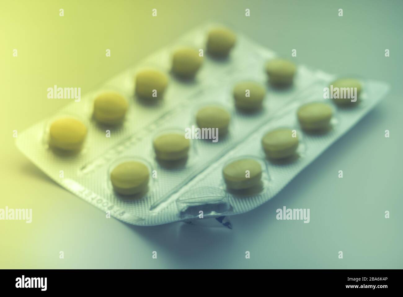 Blister mit gelben Vitaminen oder Pillen auf dem Tisch, ein Vitamin wird bereits gegessen, Nahaufnahme, Seitenansicht. Stockfoto