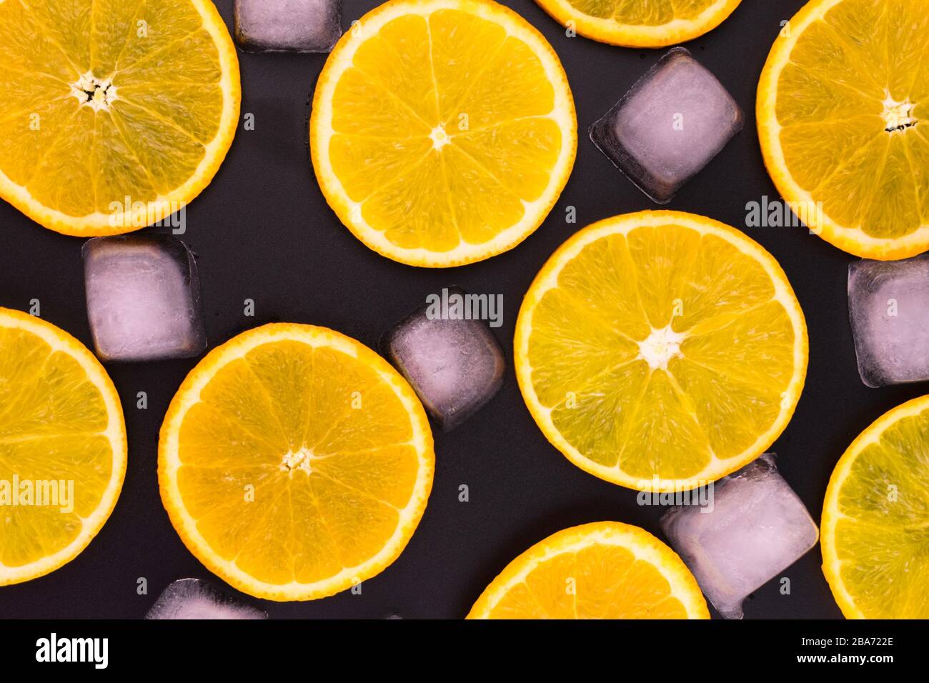 Scheiben von Orange- und Eiswürfeln auf schwarzem Hintergrund. Stockfoto