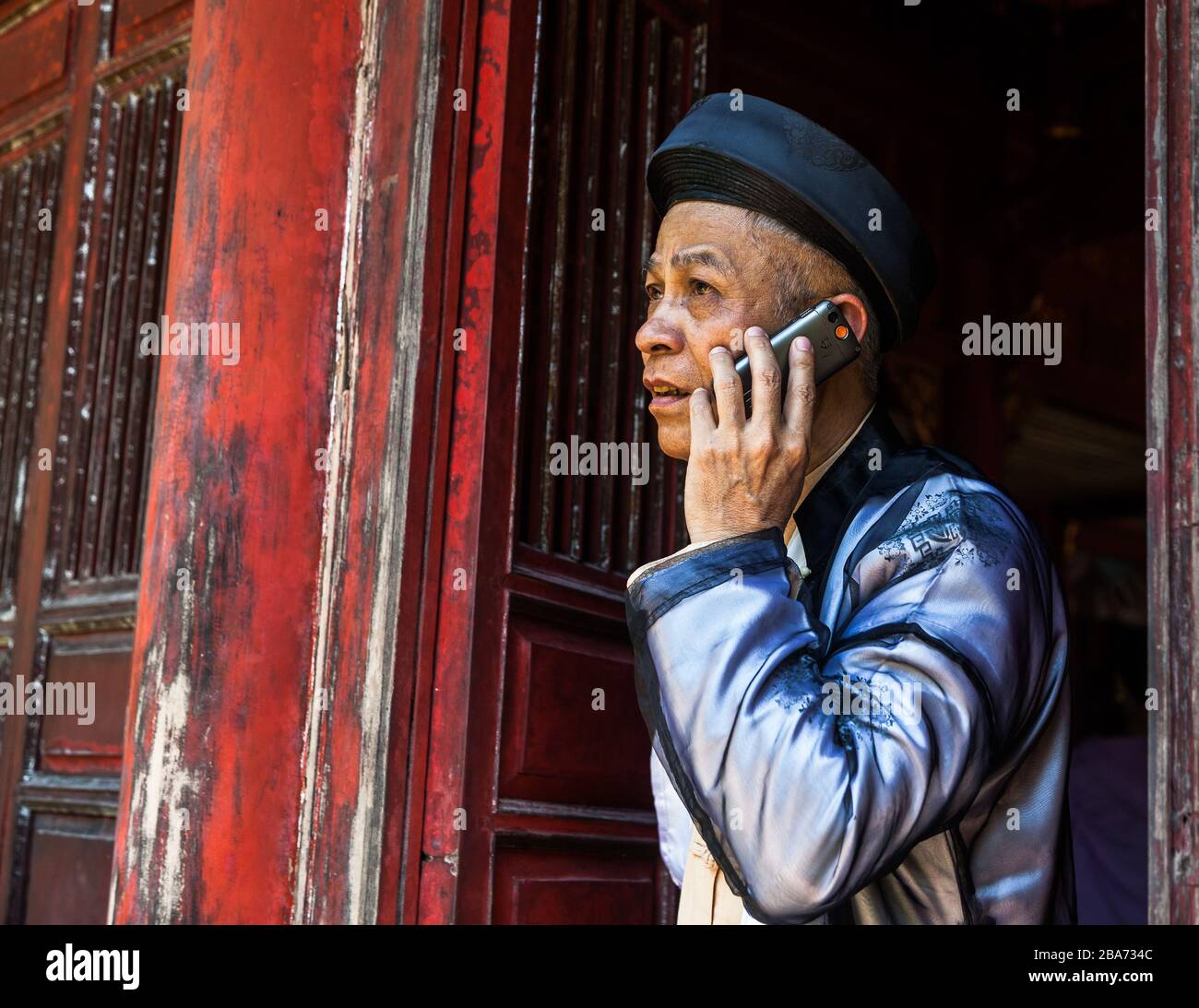 Vietnamesischer Mann im traditionellen Kleid auf Handy Stockfoto
