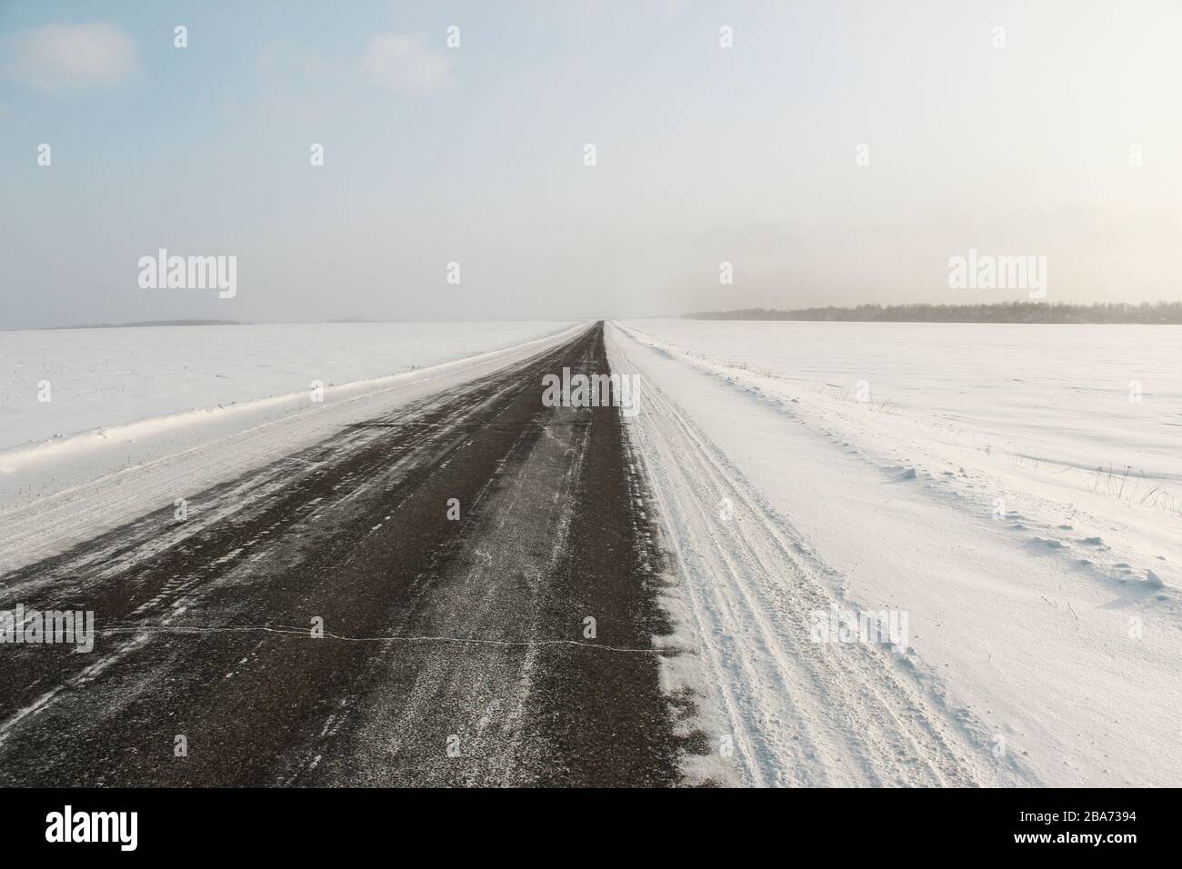Die Straße durch die schneebedeckten Felder Stockfoto