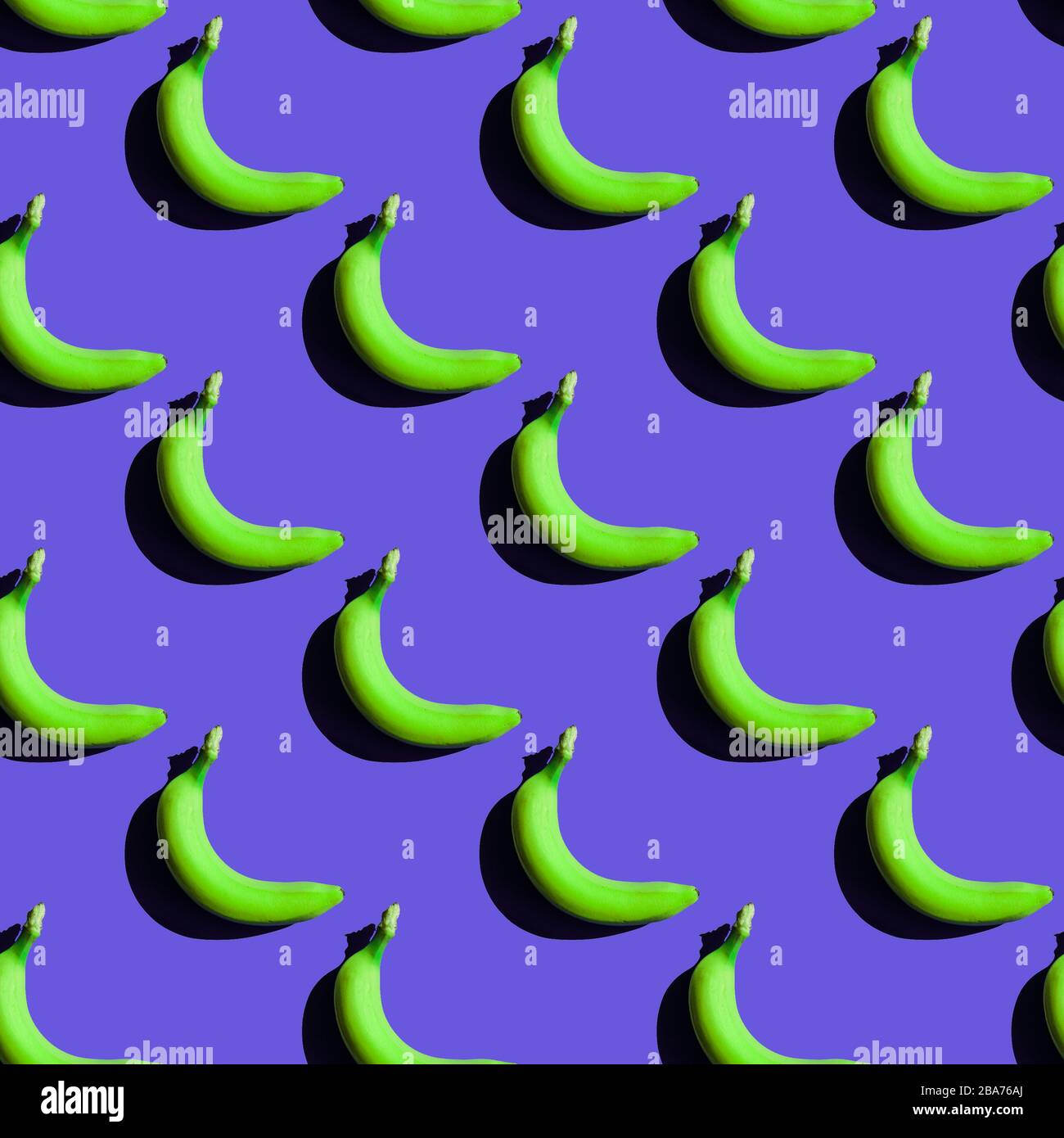 Nahtloses grünes Bananenmuster. Kreatives, lustiges Essen auf blauem Hintergrund. Frische Fruchttextur der Saison mit starken Schatten Stockfoto