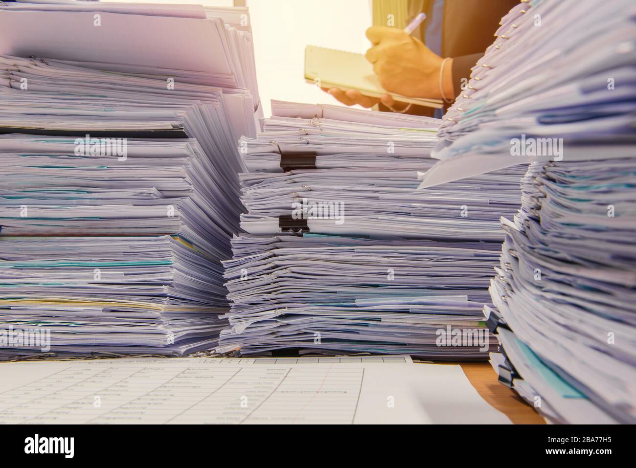 Dokumente auf Schreibtisch stapeln sich hohe warten verwaltet werden. Stockfoto