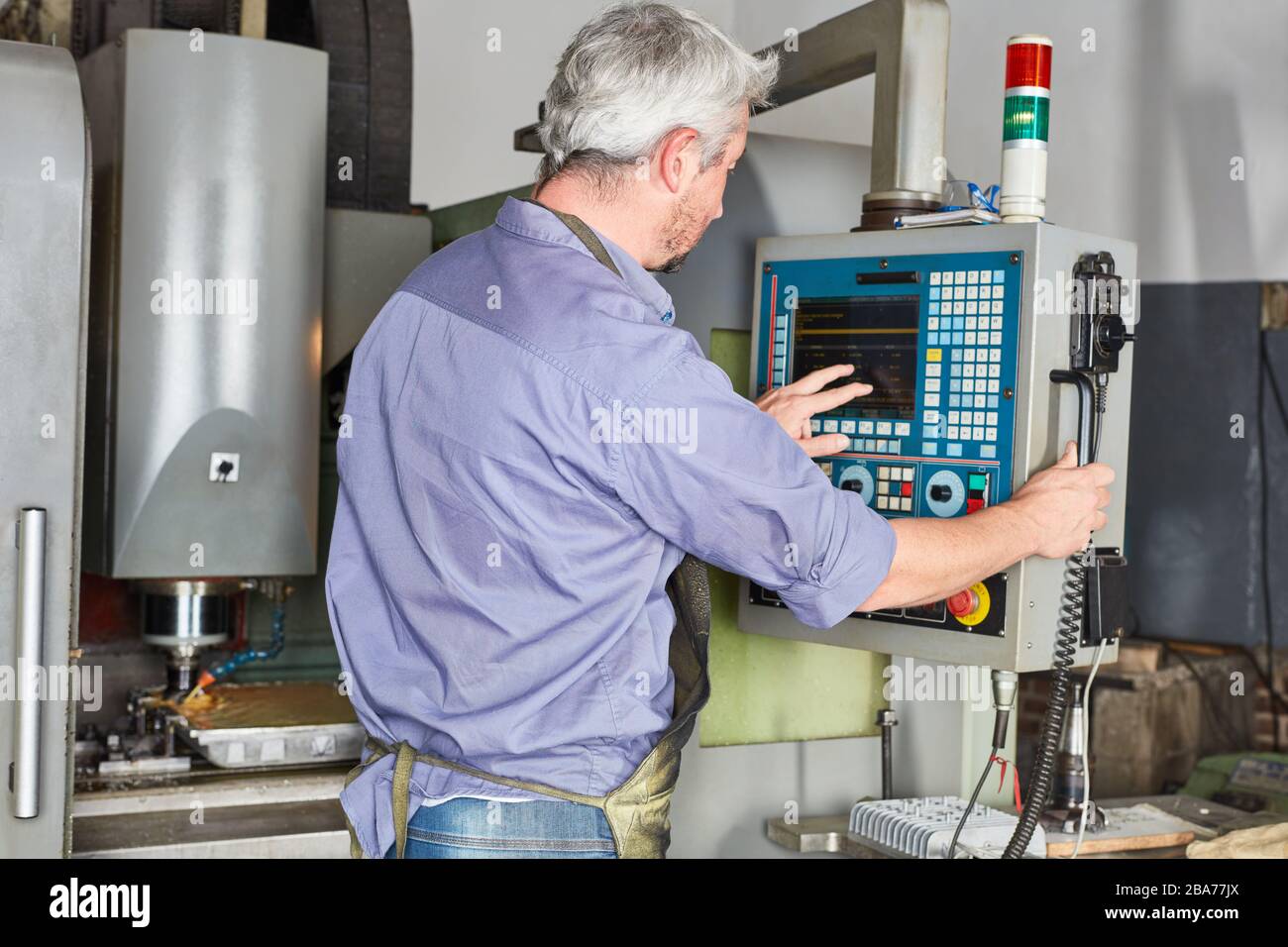 Arbeiter in einer Metallfabrik bedienen den Touchscreen einer CNC-Fräsmaschine Stockfoto Arbeiter in einer Metallfabrik bedienen den Touchscreen einer CNC-Fräsmaschine Stockfoto