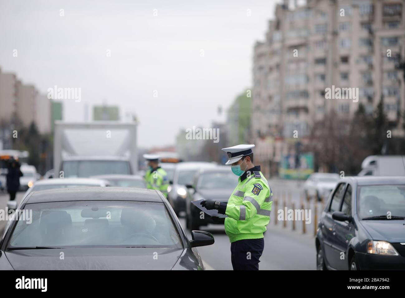 Bukarest, Rumänien - 25. März 2020: Rumänischer Verkehrspolizist zieht über ein Auto, um nach den Ausweispapieren des Fahrers zu suchen. Stockfoto