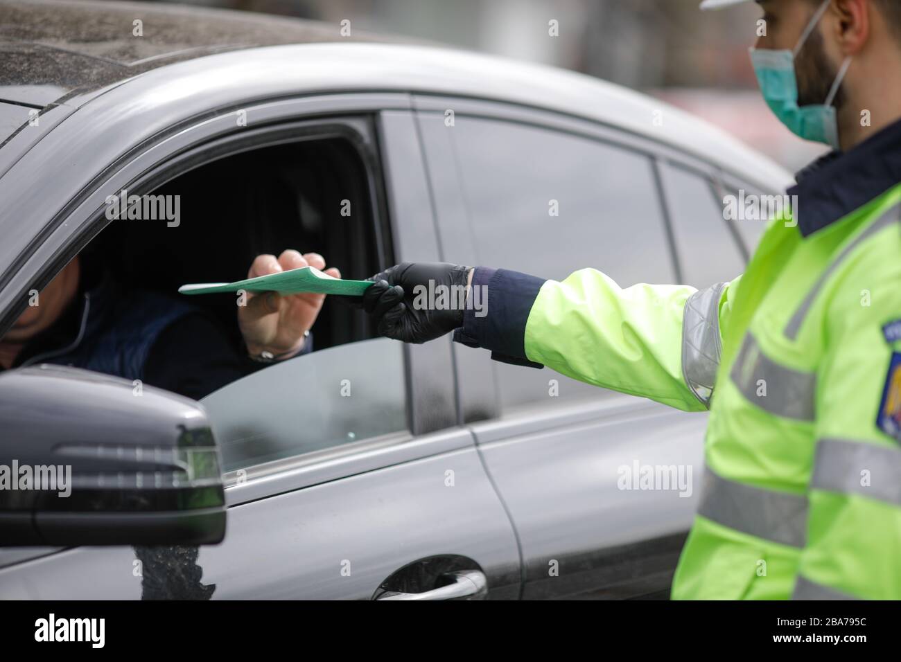 Bukarest, Rumänien - 25. März 2020: Rumänischer Verkehrspolizist zieht über ein Auto, um nach den Ausweispapieren des Fahrers zu suchen. Stockfoto