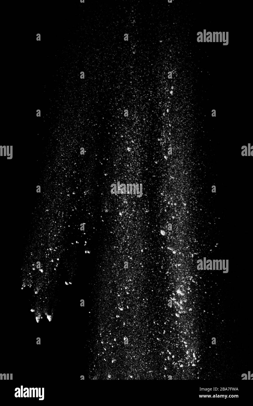 Weißer Staub ähnlich wie Mehl und Schnee wird auf schwarzem Grund 2020 aktiv isoliert verstreut Stockfoto