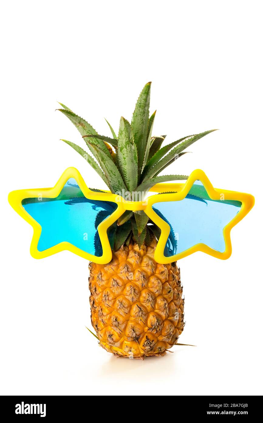 Einzelne reife Ananas mit großer blauer und gelber Partybrille in Sternform, isoliert auf weißem Hintergrund, vertikaler Komposition, Party-Konzept. Stockfoto