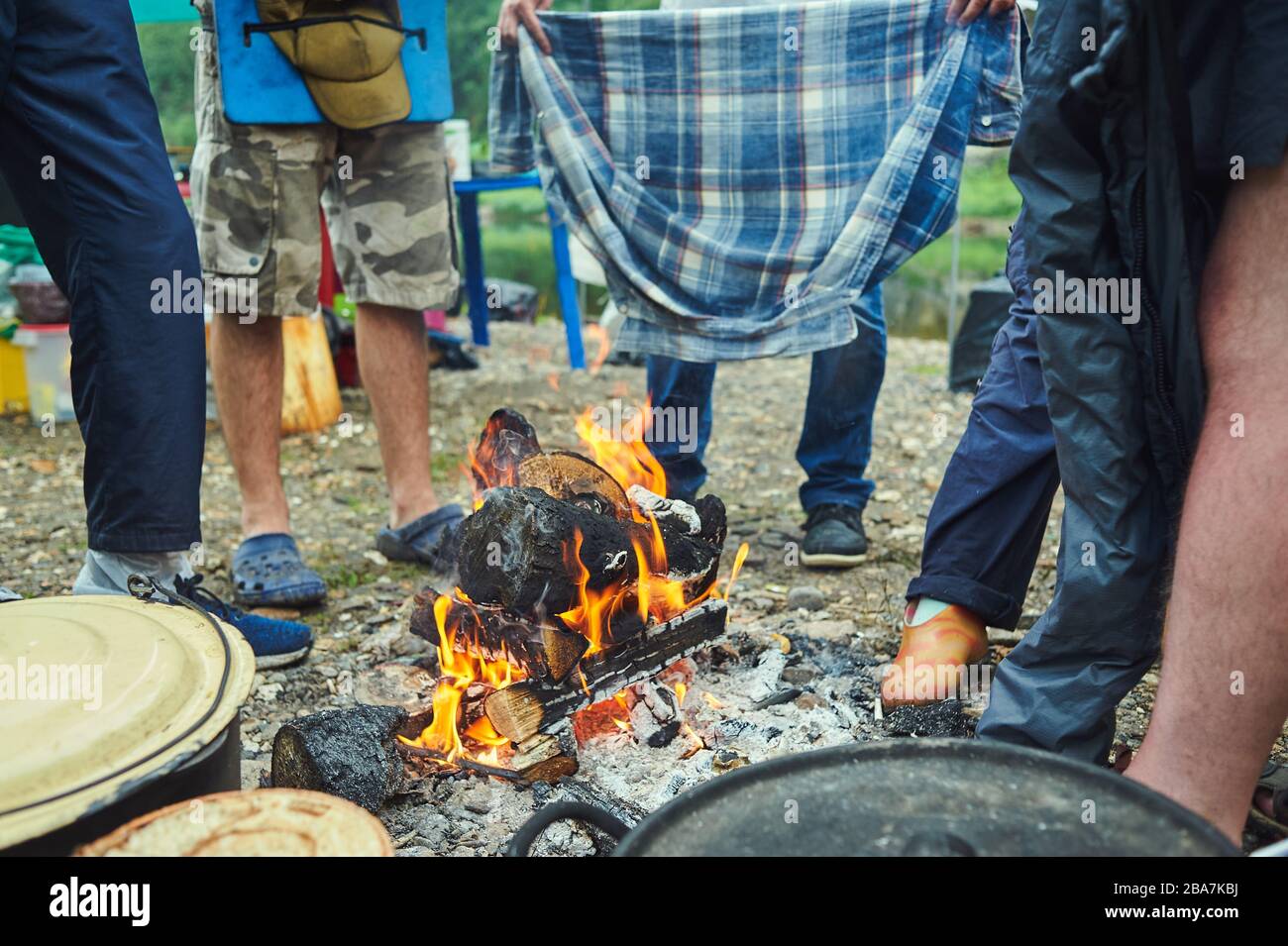 Nasse Touristen wandern um das Lagerfeuer und trocknen ihre Kleidung. Im Wald durchnässt Stockfoto