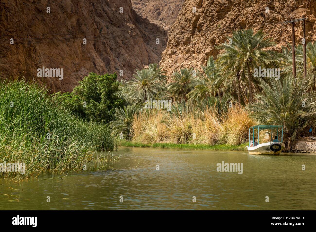 Ein kleines Boot, das Touristen zu Beginn der Wanderung nach Wadi Shab im Oman über den Fluss führt. Stockfoto