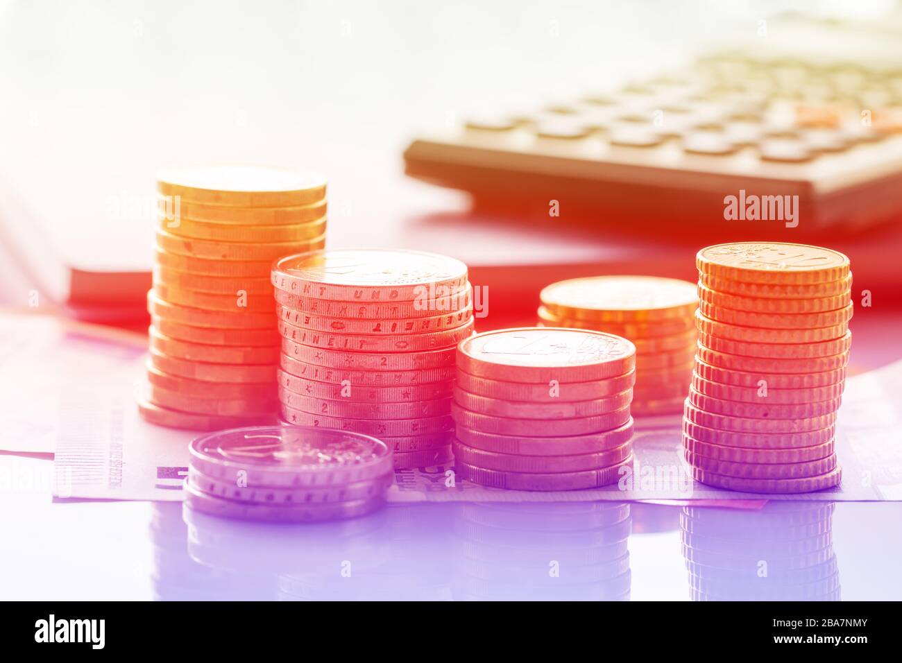 Euro-Münzen auf Euro-Banknoten mit Taschenrechner für Hintergründe im Stapel. Deutschland Euromünzen im Stapel auf Eurobanknoten mit Taschenrechner, für Hintergr Stockfoto