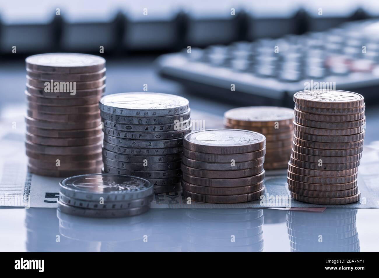 Euro-Münzen auf Euro-Banknoten mit Taschenrechner für Hintergründe im Stapel. Deutschland Euromünzen im Stapel auf Eurobanknoten mit Taschenrechner, für Hintergr Stockfoto