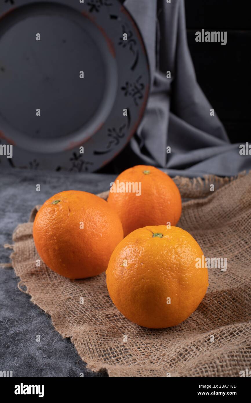 Frische Orangen mit einer dunklen Platte dahinter. Stockfoto