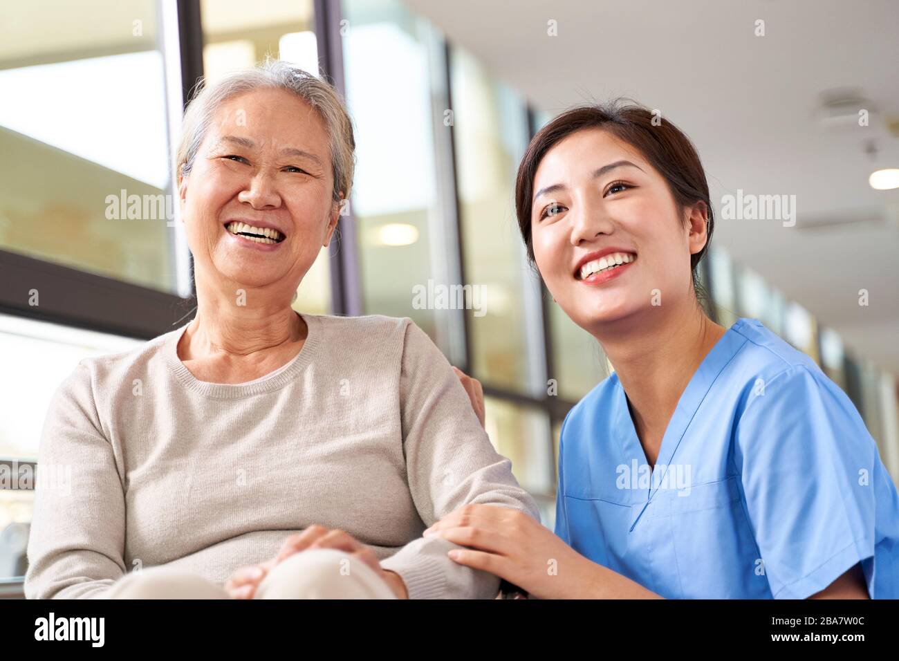 Asiatische Seniorin und ihre Pflegeperson lächeln mit der Kamera Stockfoto