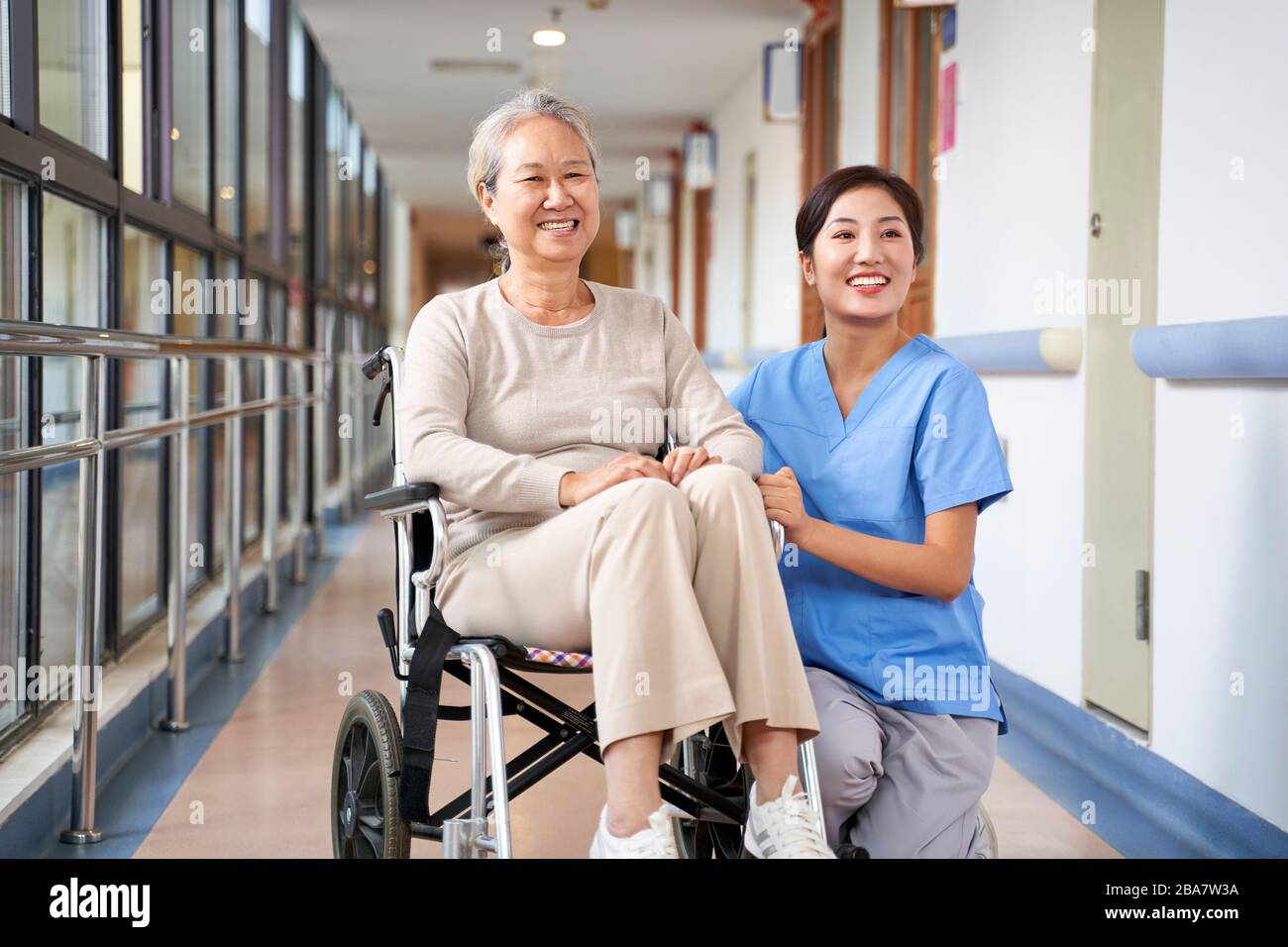 Asiatische Seniorin und ihre Pflegeperson lächeln mit der Kamera Stockfoto