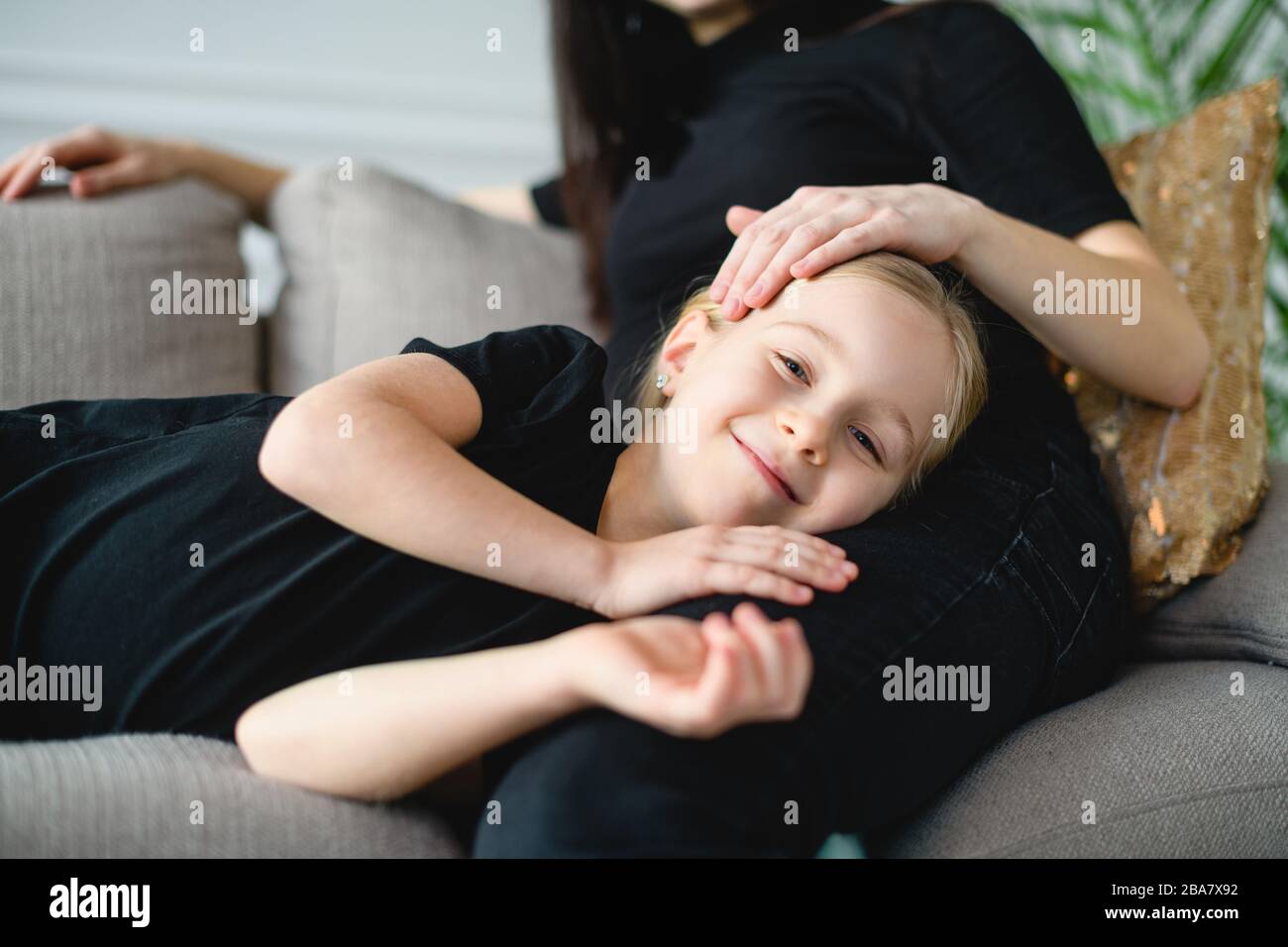 Kleines glückliches Mädchen in den Knien der Mutter Stockfoto
