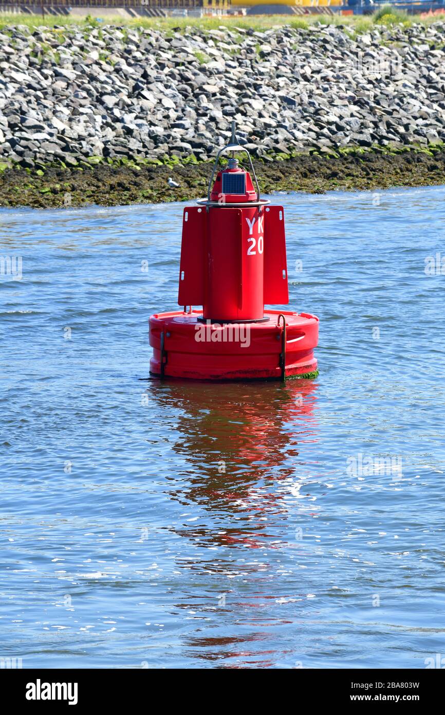 Leuchtend rote Markerboje, die in der Nähe der Küstenlinie als Signal für die Schiffsdurchfahrt auf der Nieuwe Maas in Rotterdam verankert ist Stockfoto
