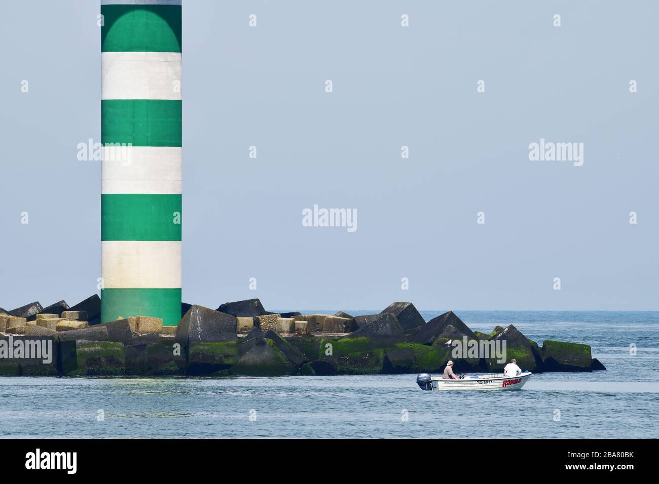 Kleines Fischerboot am Eingang des Haupthafens Rotterdam vor dem Hintergrund eines grün-weiß gestreiften Radars Stockfoto