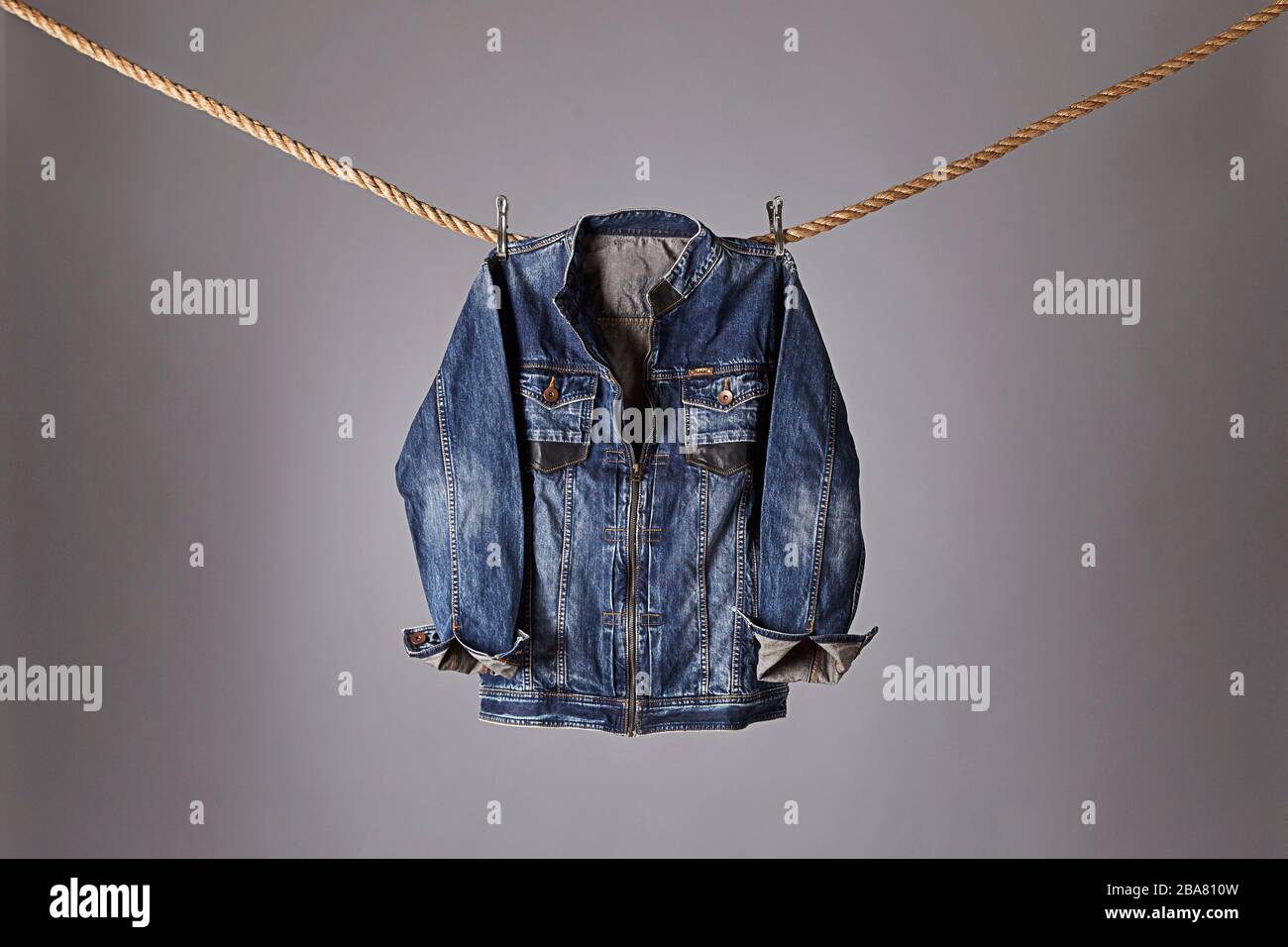 Eine coole blaue Jeansjacke, die an einem Seil hängt Stockfoto