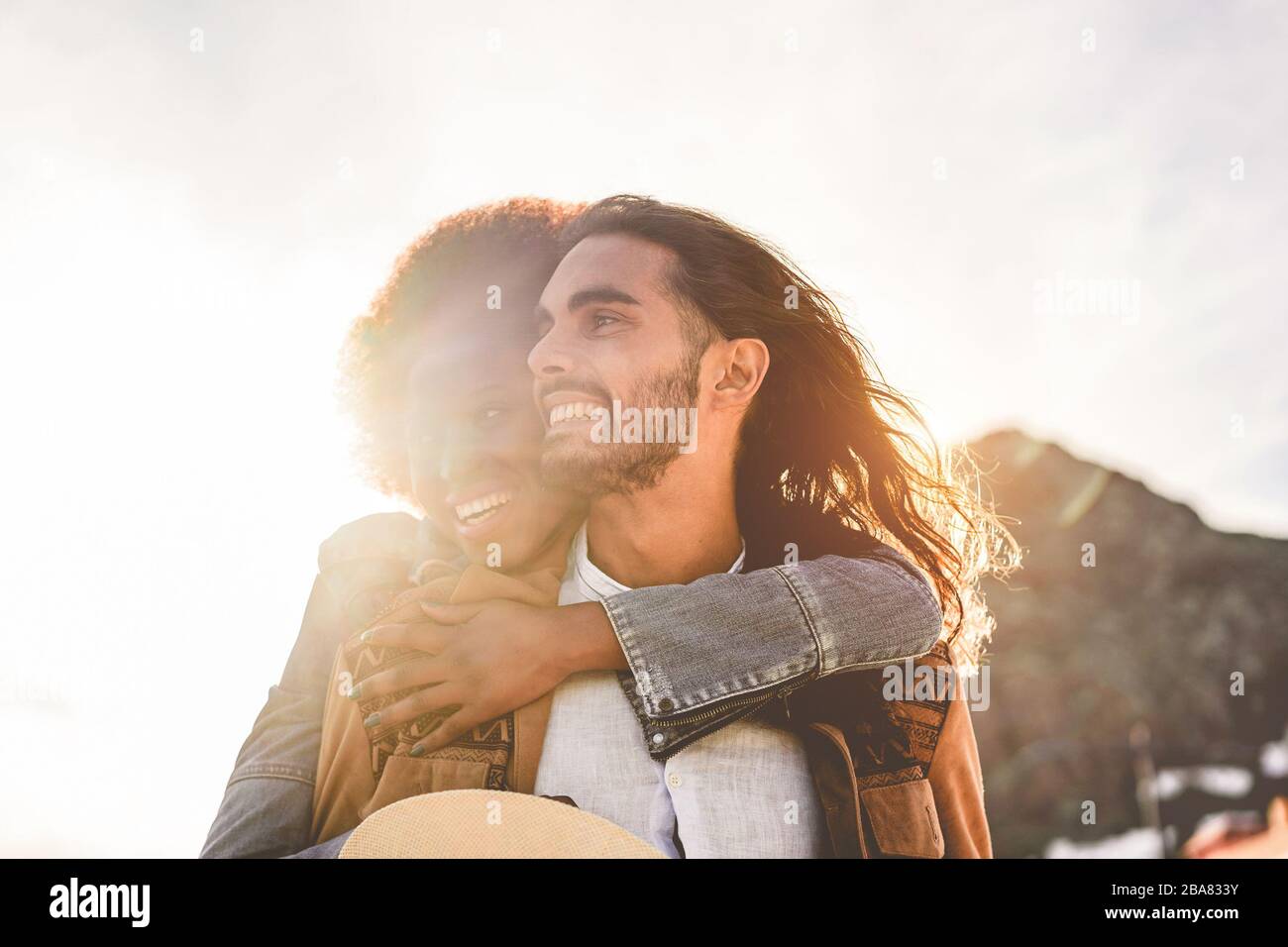 Glückliche Paare, die zarte Momente im Freien bei Sonnenuntergang haben - junge Liebhaber, die gemeinsam Spaß haben - Liebe, Beziehung und muti ethnisches Konzept - konzentrieren sich auf den Menschen Stockfoto