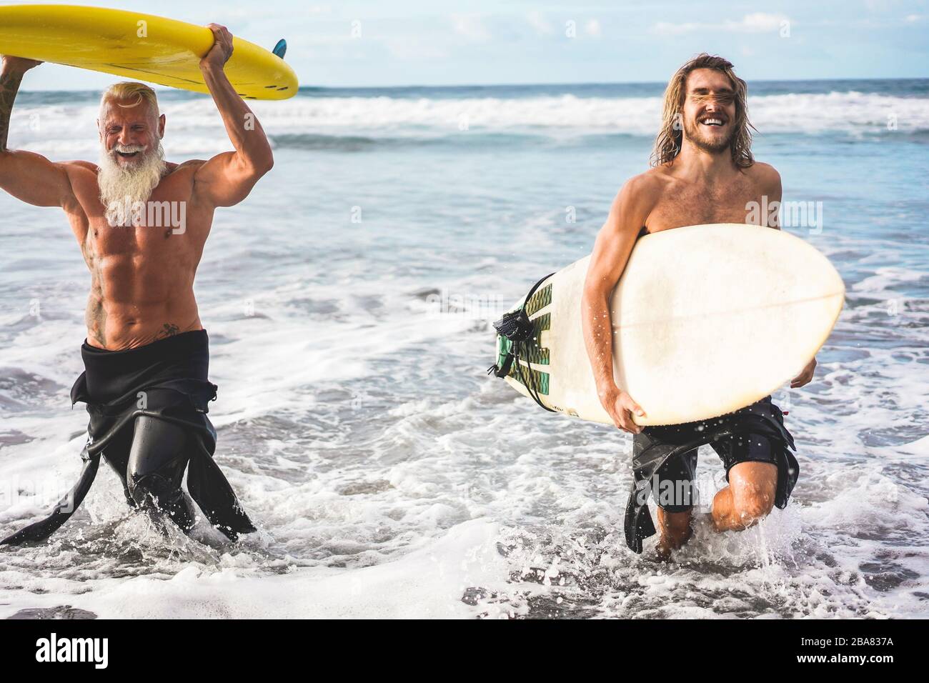 Mehrgenerationige Freunde, die am tropischen Strand surfen - Familienmitglieder haben Spaß am Extremsport - fröhliches älteres und gesundes Lifestyle-Konzept Stockfoto