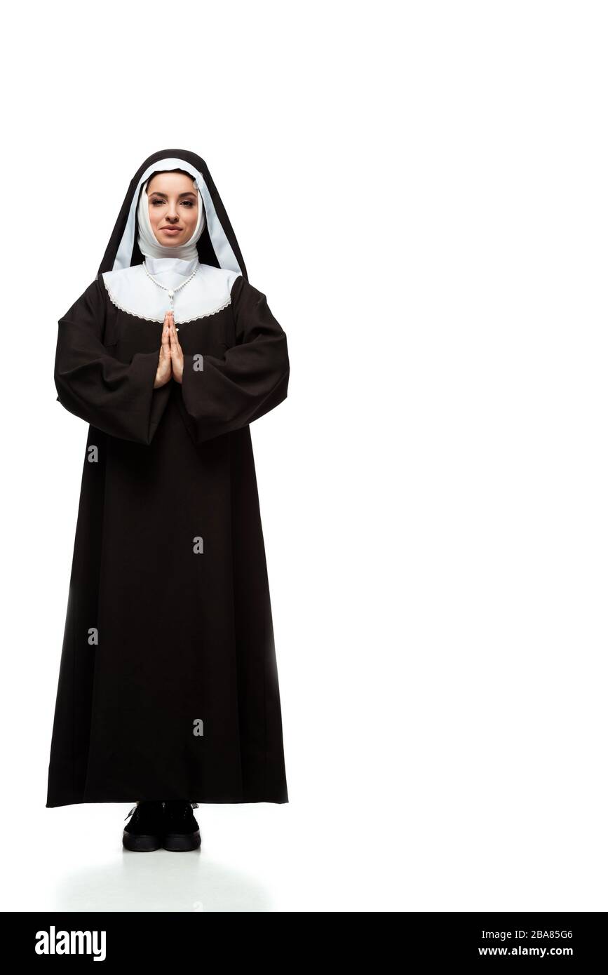 Schöne junge betende Nonne, die auf Weiß steht Stockfoto