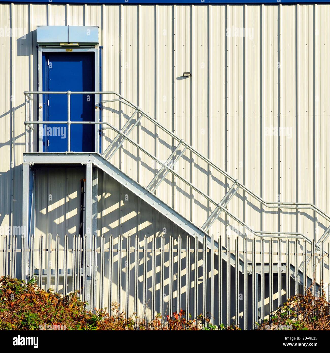 Metalltreppe an der Seite des Gebäudes, die zur blauen Tür im ersten Stock des modernen Lagers führt Stockfoto