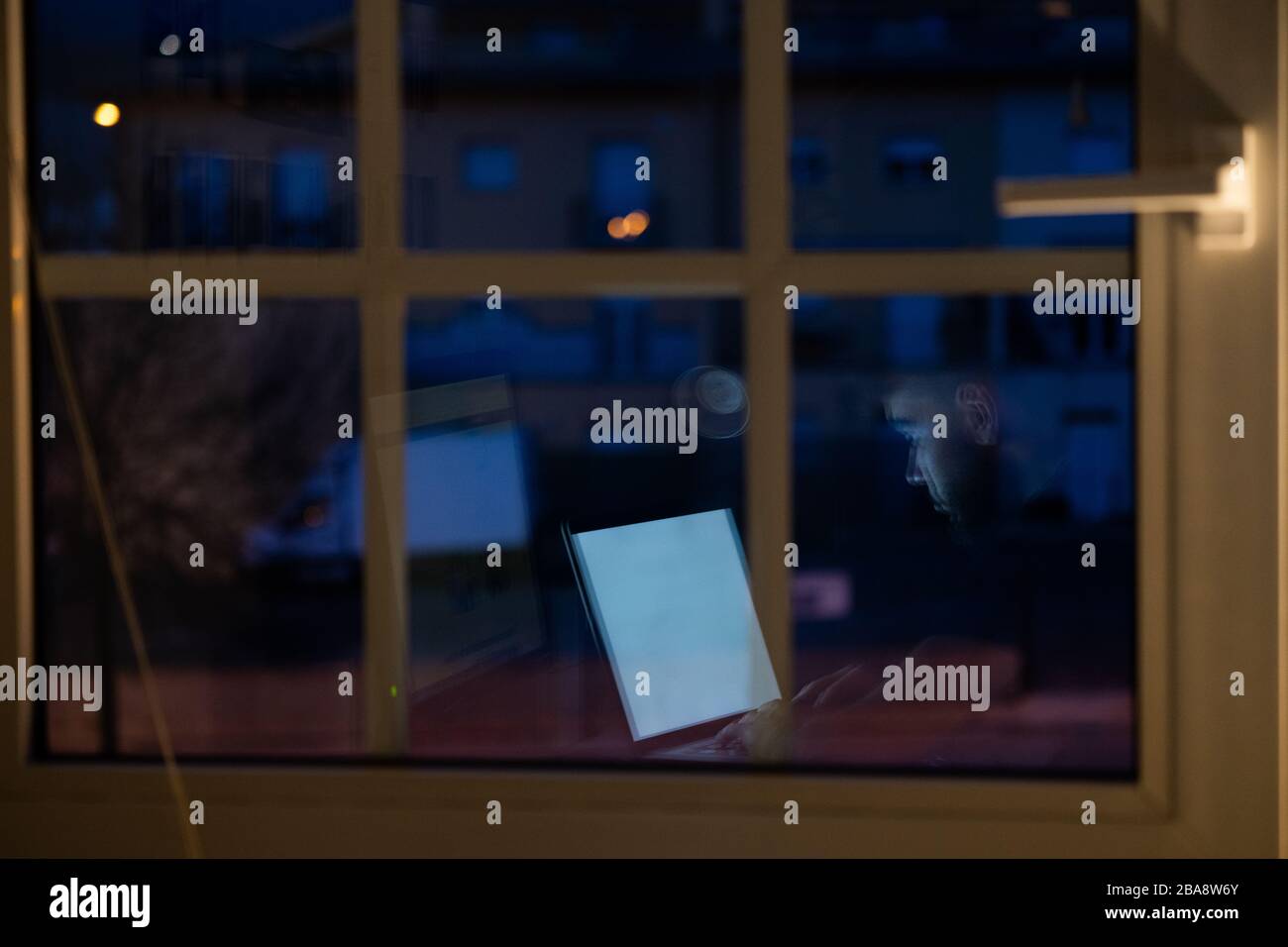 Person, die nachts mit dem Computer von zu Hause aus arbeitet, Spiegelung des Fensters Stockfoto