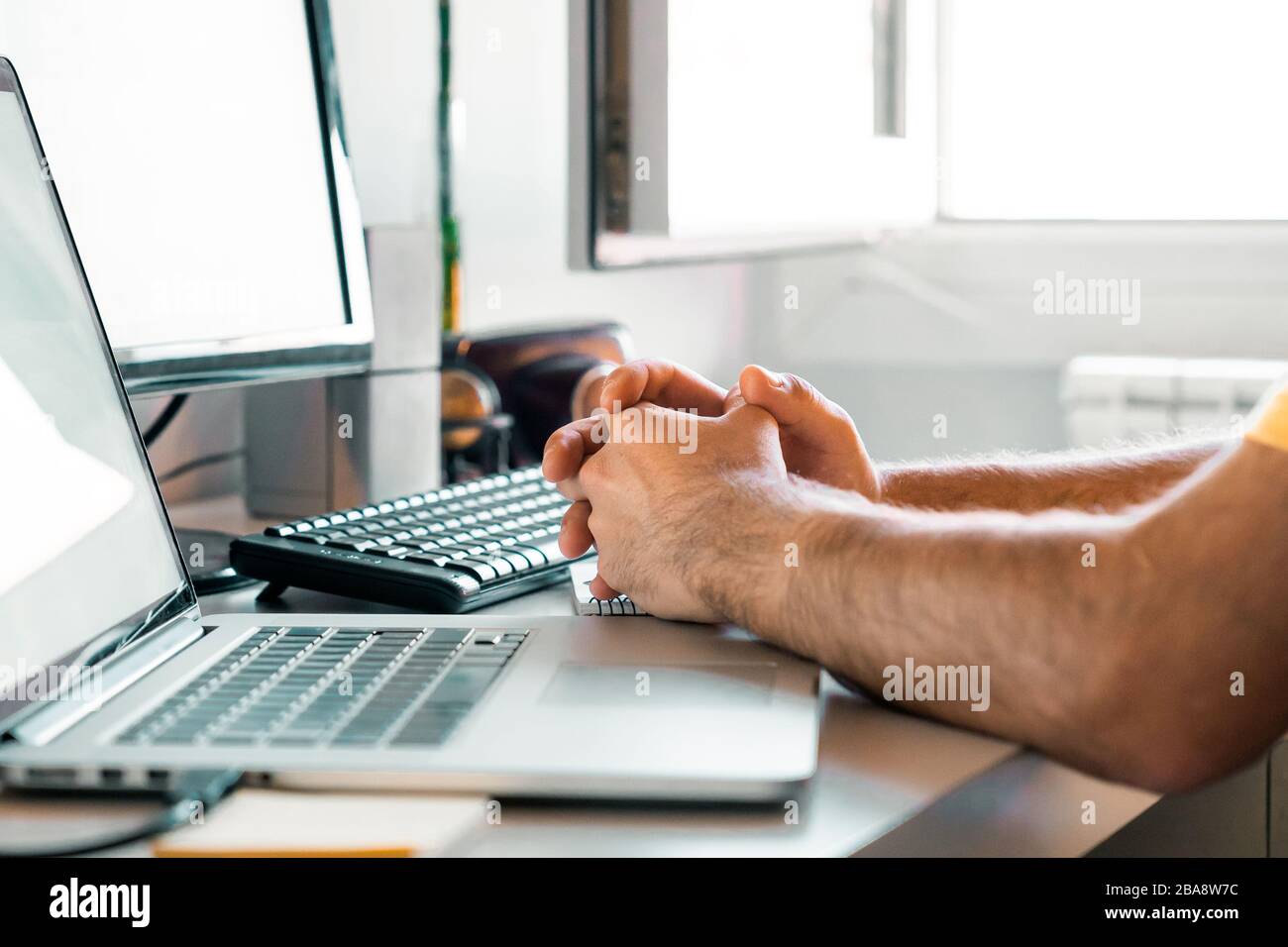 Person, die über die Arbeit von zu Hause aus an ihrem Schreibtisch mit Computern nachdenkt Stockfoto