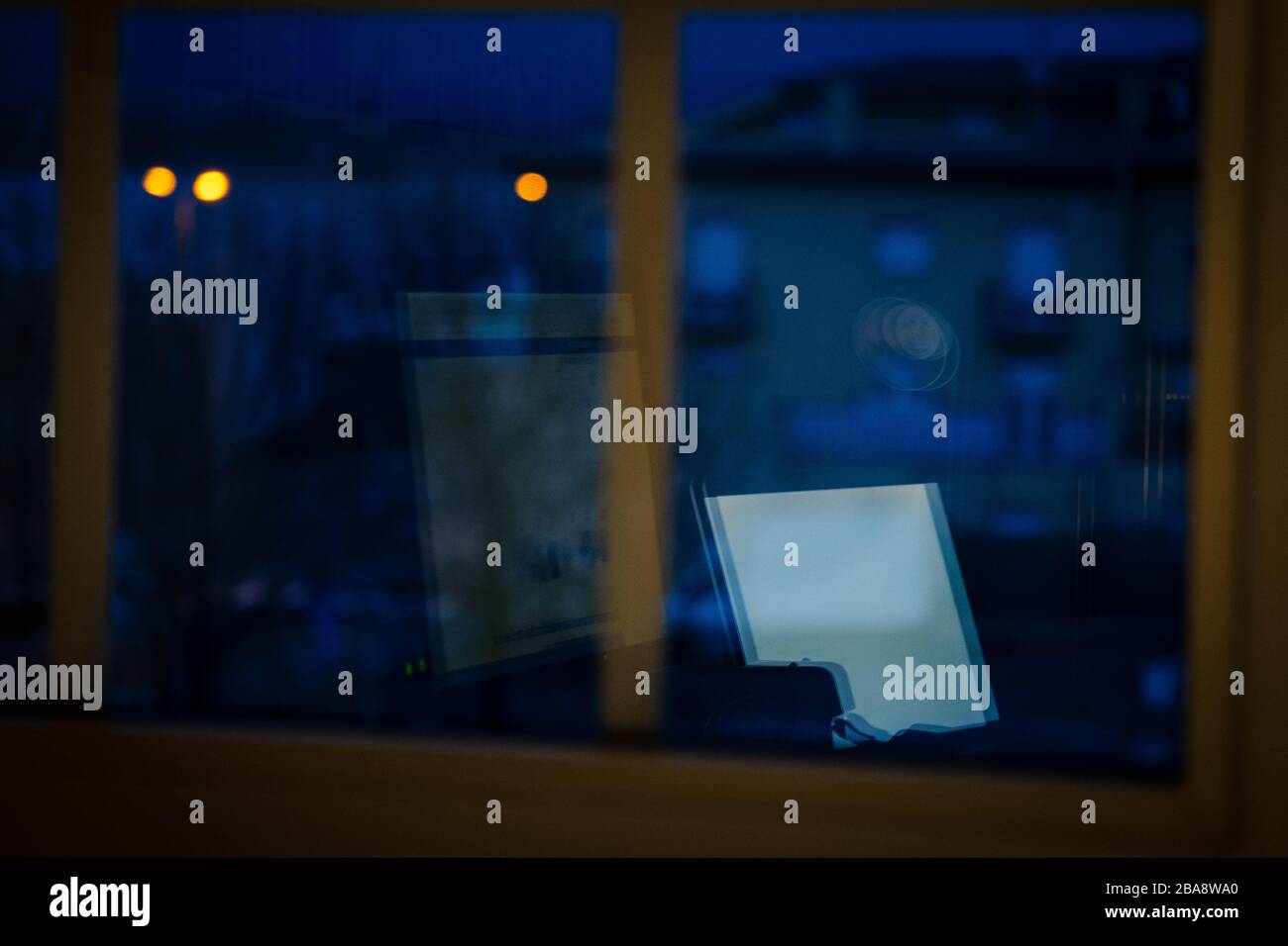 Spiegelung eines Computers nachts aus dem Fenster, Arbeit von zu Hause aus in der Nacht Stockfoto