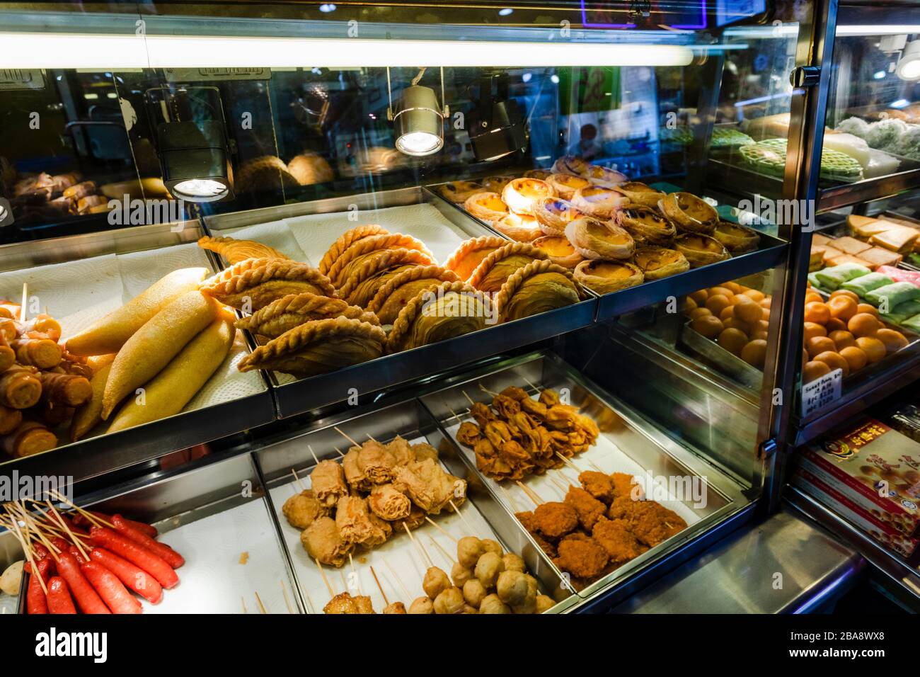 Verschiedene Gebäckstücke und andere warme Speisen werden an einem Verkaufsstand in Bugis, Singapur angeboten Stockfoto