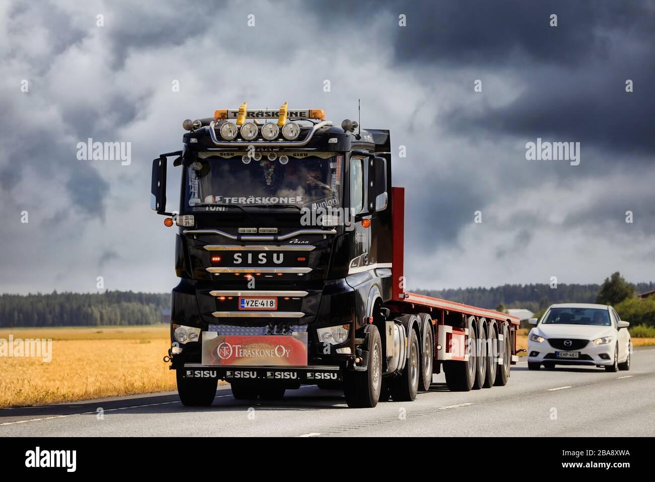 Schwarzer personalisierte Sisu Polar Tieflader Truck Trailer Teraskone Oy mit Geschwindigkeit auf der Straße unter dramatischem Himmel. Luopajarvi, Finnland. August 2019. Stockfoto