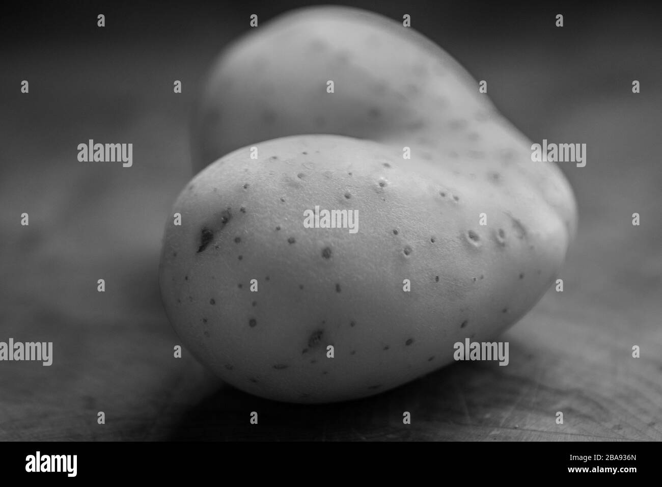 Isolierte Nahaufnahme einer einzelnen herzförmigen Rohkartoffel in Schwarzweiß Stockfoto