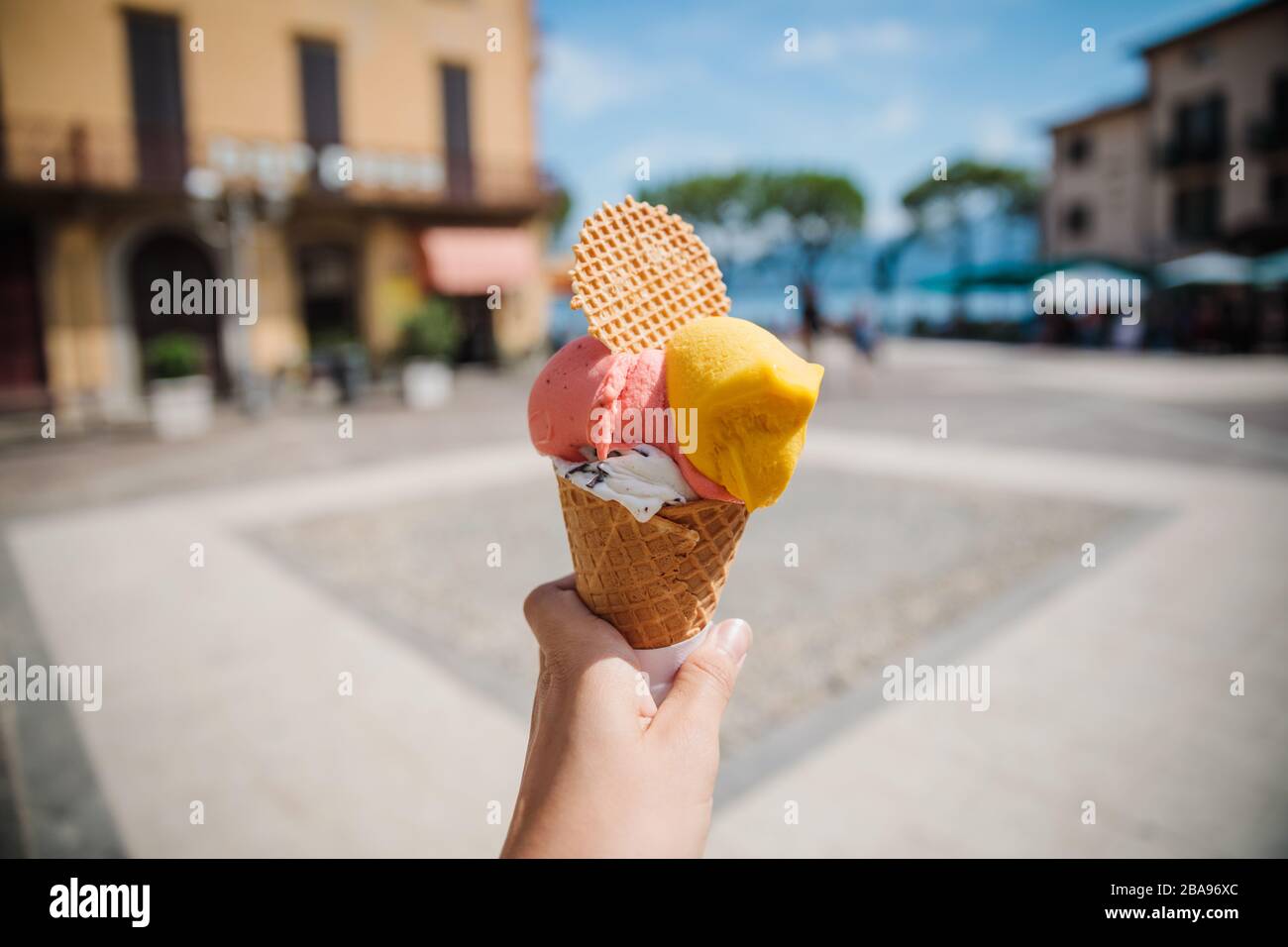 Händekegel mit farbenfrohem italienischem Gelato-Eis in der Stadt Menaggio in der Nähe des Comer Sees in Norditalien im Sommertag Stockfoto