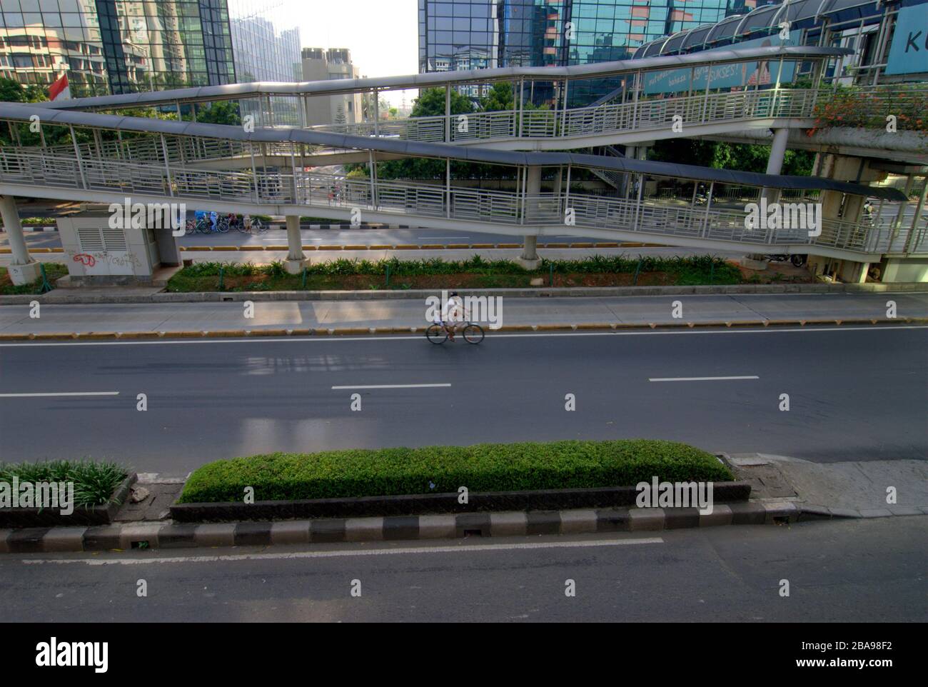 Eine Mutter und ihre Tochter fahren mit dem Fahrrad auf einer leeren Straße in Jakarta, Indonesien. Stockfoto