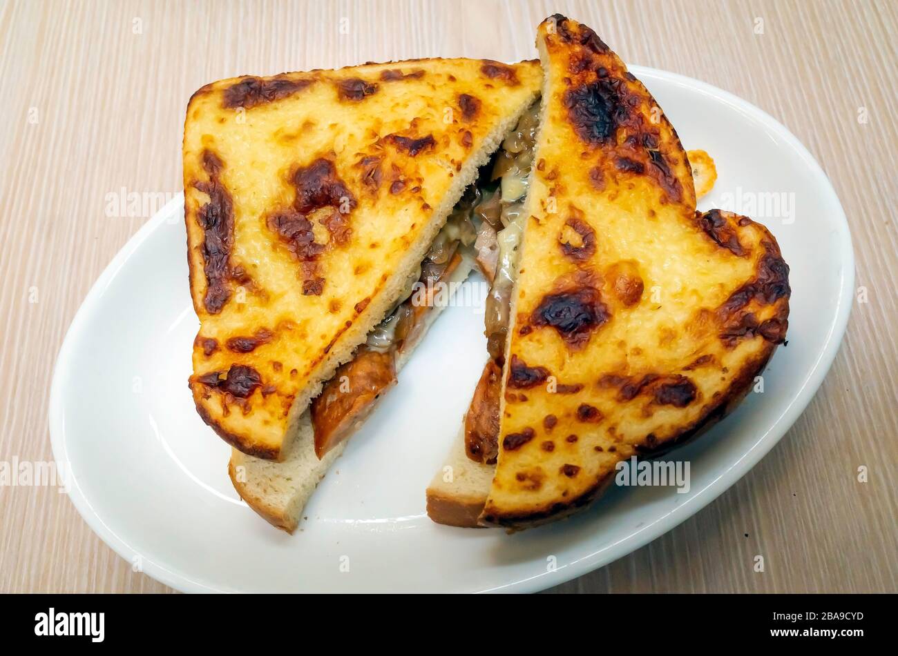 Schlichter Snack geröstete Wurst und Zwiebel-Sandwich in Weißbrot mit gegrilltem Käse obenauf Stockfoto