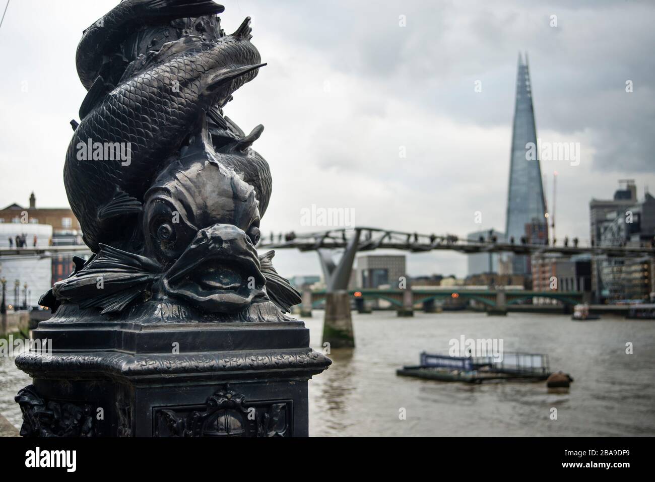 Verzierter Lampenpfosten mit Fischdesign aus Gusseisen und Shard und Millennium Bridge im Hintergrund, London, Großbritannien Stockfoto