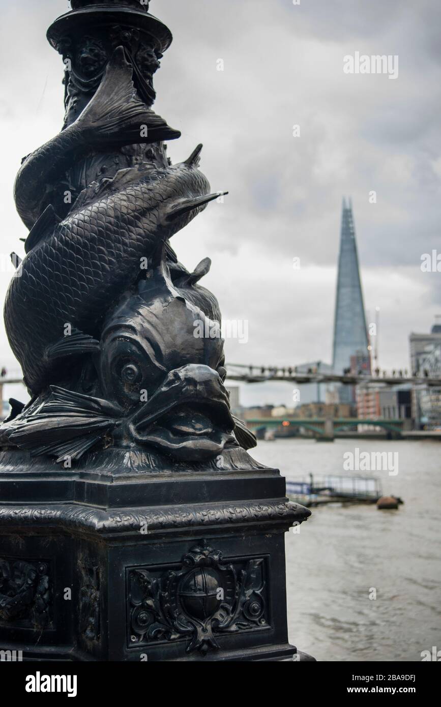 Verzierter Lampenpfosten mit Fischdesign aus Gusseisen und Shard und Millennium Bridge im Hintergrund, London, Großbritannien Stockfoto