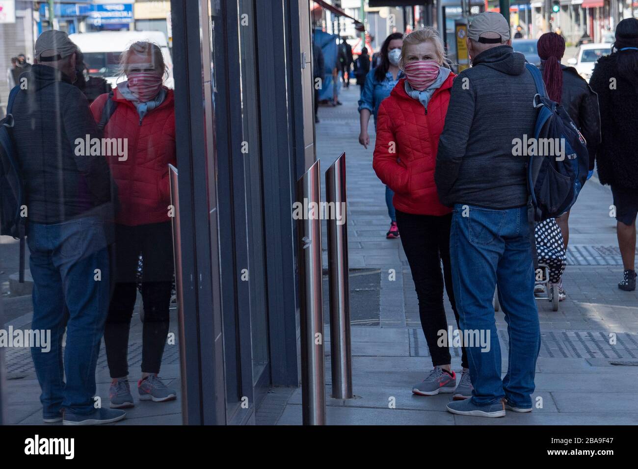 West Norwood, England. März 2020. Eine Frau, die eine Gesichtsmaske trägt, wartet während der Coronavirus Pandemie außerhalb des Supermarktes in Island in South London. Gutschrift: Sam Mellish / Alamy Live News Stockfoto