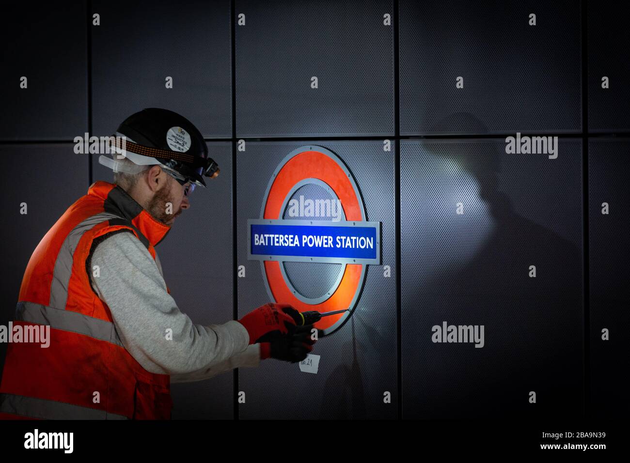 Ein Ingenieur installiert ein Rundel auf dem Bahnsteig an der Battersea Power Station, London Underground Station Stockfoto