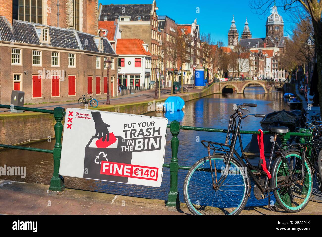 Warnschild auf Englisch über einem Kanal mit der Aufschrift "Put Your Trash in the bin" im Rotlichtviertel in der Innenstadt von Amsterdam. Stockfoto