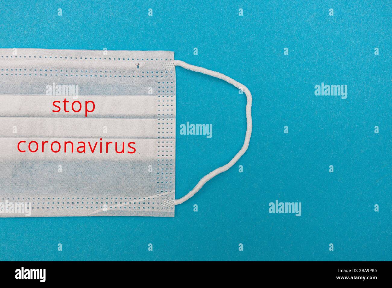 Medizinische Einwegmaske auf blauem Grund mit der Aufschrift STOP coronavirus Kovid 19. Weltpandemic Coronavirus. Stoppen Sie die Pandemie Stockfoto