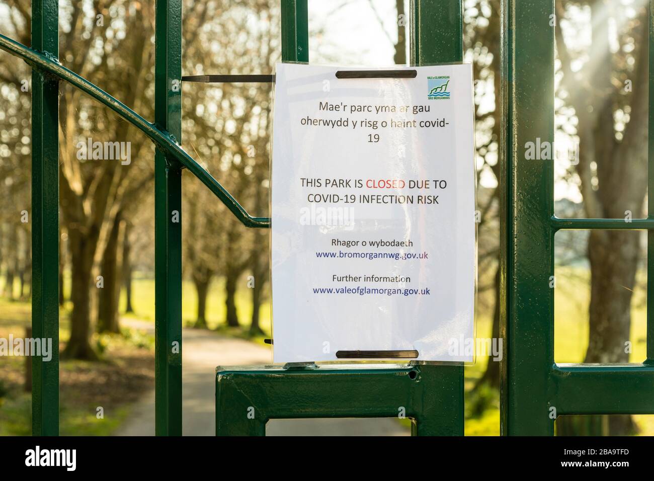 Ein leerer Park hinter verschlossenen Toren an einem sonnigen Tag während der Coronavirus-Krisen. Eine Mitteilung des Rates von Glamorgan in walisischer und englischer Sprache ist beigefügt. Stockfoto