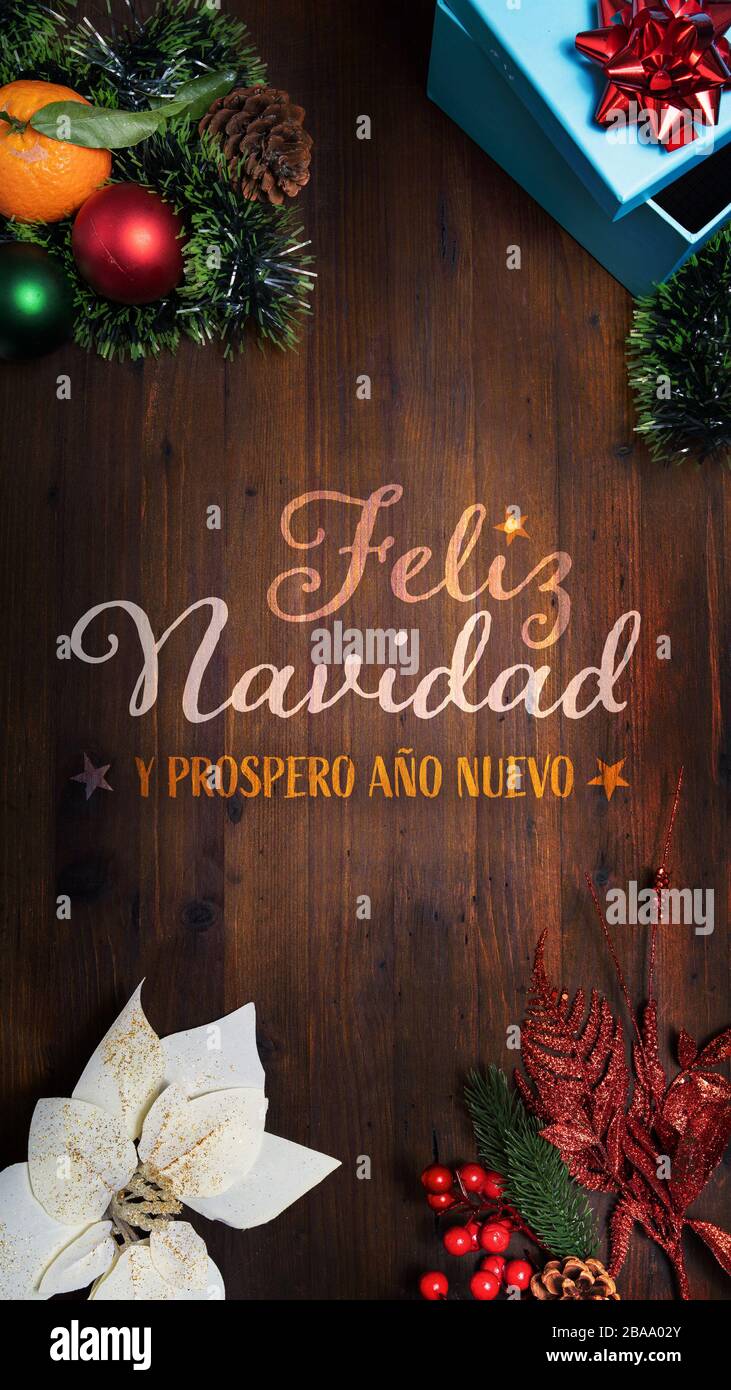 "Feliz Navidad y prospero Año Nuevo" t.i. Frohe Weihnachten und ein glückliches Neujahr in spanischer Sprache auf Holzhintergrund mit vertikaler Dekorationsansicht Stockfoto