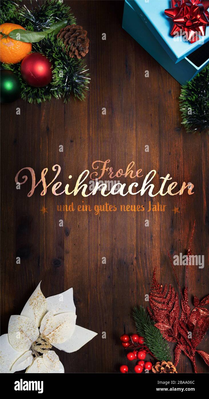 "Frohe Weihnachten und ein gutes neues Jahr" t.i. Frohe Weihnachten und frohes neues Jahr in deutscher Sprache auf Holzhintergrund mit Dekoration Smartph Stockfoto