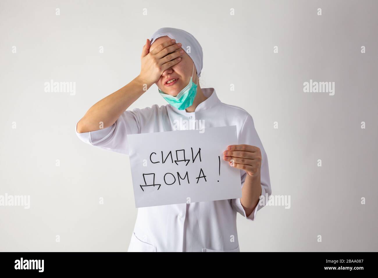 Der Hausarzt in Maske hält eine Tablette in den Händen - bleib zu Hause Stockfoto