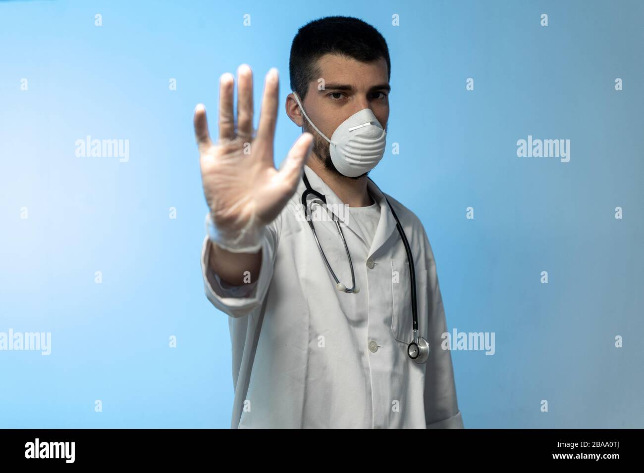 COVID 19 Concept stoppen. Junger Arzt in medizinischer Uniform mit einer schützenden Gesichtsmaske und Handschuhen, die Stop Hands Geste für Stop Coronavirus Ausbruch zeigen Stockfoto