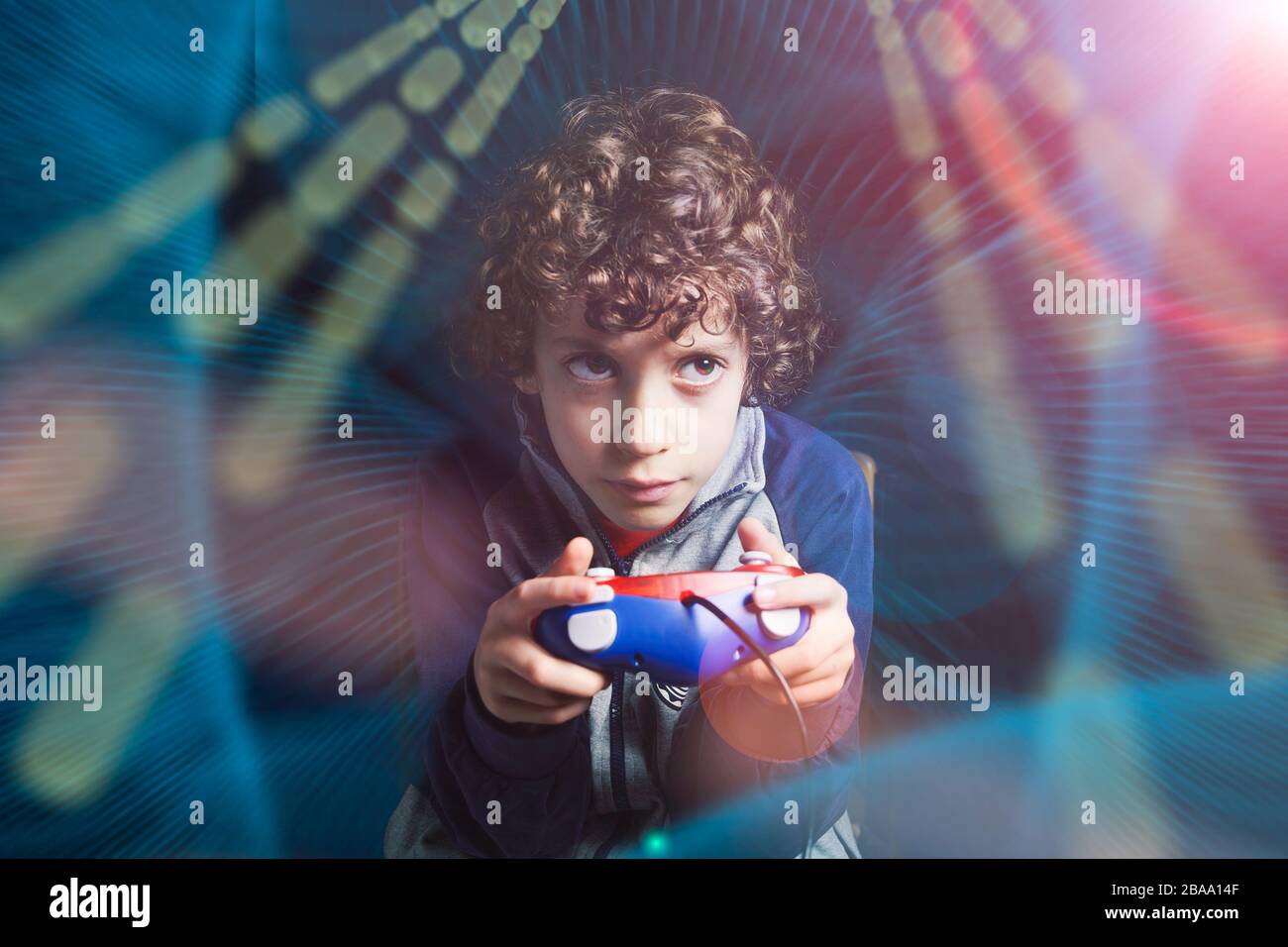 Gamer Kid. 7-8 Jahre altes Kind, das einen Konsolenspiel-Controller hält, das ein Videospiel in einem computergrafischen Licht-Kompositions-Ambient spielt. Studio gedreht. Ga Stockfoto