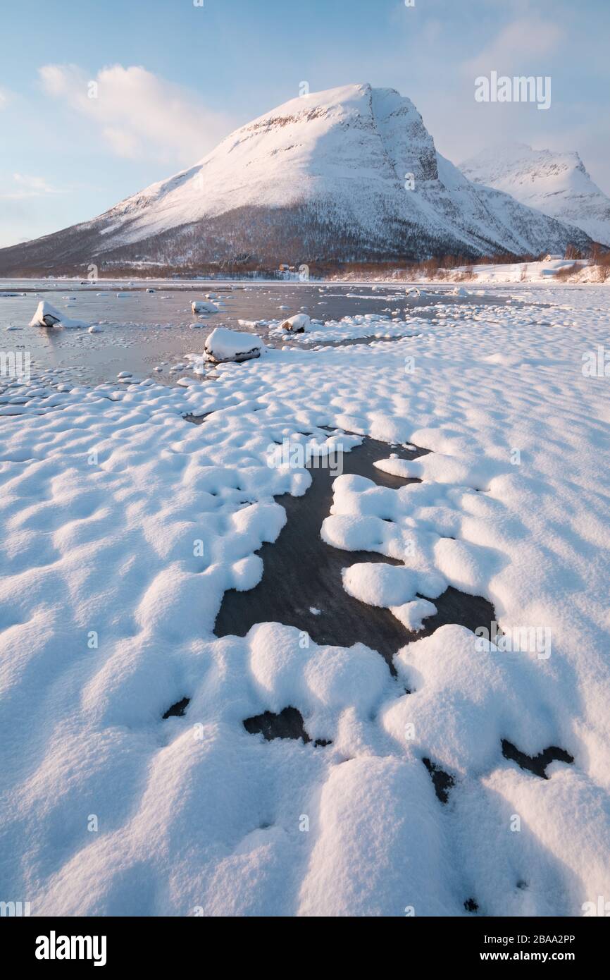 Pink am frühen Morgen leuchtet auf schneebedeckten Bergen im arktischen norwegen auf, eine superbreite Panoramaszene. Blick auf den Winter auf den schneebedeckten Berg in Scandina Stockfoto
