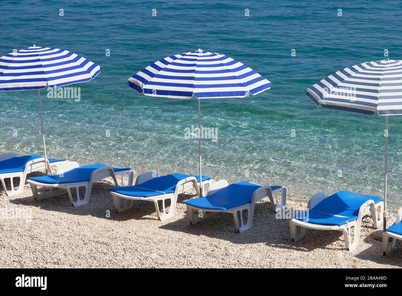 Blaue Sonnenschirme und Sonnenliegen für Entspannung im Resort. Sommerferien und Reisen zum Meer. Kostenpflichtiger Service an den komfortablen Stränden. Stockfoto