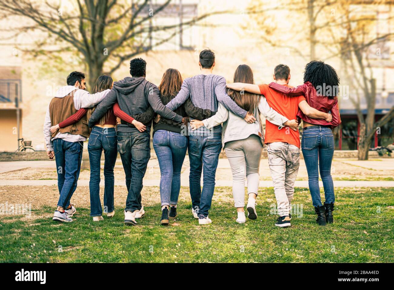 Eine Gruppe junger Multiracial Leute, die im Freien in einem Park Arm um Schultern laufen. Studenten, die ein Lifestyle-Konzept mit Diversität leben. Stockfoto